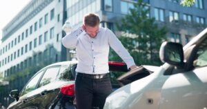 A man standing by his rental car after a crash. Use this rental car accident guide to learn how to handle these collisions.