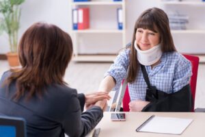 A personal injury lawyer in San Francisco, offering reassurance to an injured woman with a crutch, neckbrace, and arm sling.