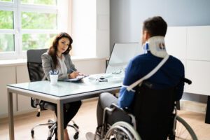 An injured man in a wheelchair with a neck brace and an arm sling consulting a truck accident lawyer in San Francisco.