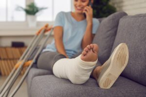 A truck accident victim with her leg in a cast on the phone with a Beverly Hills truck accident lawyer