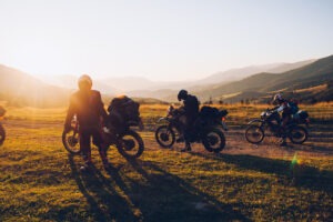 Several motorcyclists pull over to the side of the road at sunset.