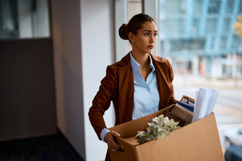 Sad,Businesswoman,With,Box,Of,Her,Belongings,Leaving,The,Office
