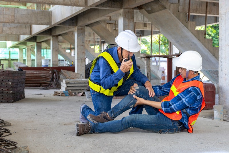 Asian factory worker having accident while working in manufacturing site while his colleague is helping for safety workplace and emergency